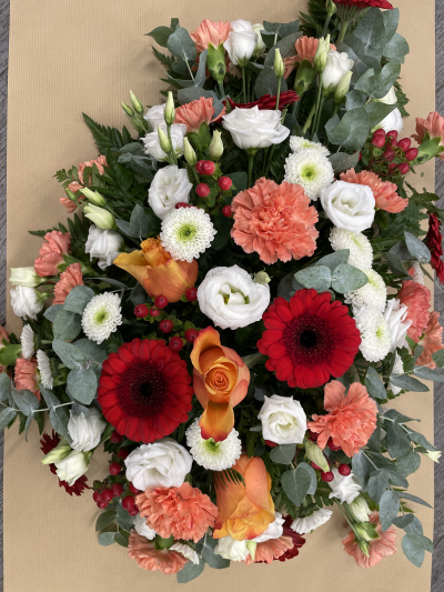 Warmest Memories Funeral Spray - A beautiful and heartfelt funeral tribute featuring a warm blend of rich reds, soft peach, vibrant orange and delicate white tones. Lovingly arranged with lush greenery, this elegant spray is a touching way to honour a loved one, celebrate cherished memories and say a final farewell.